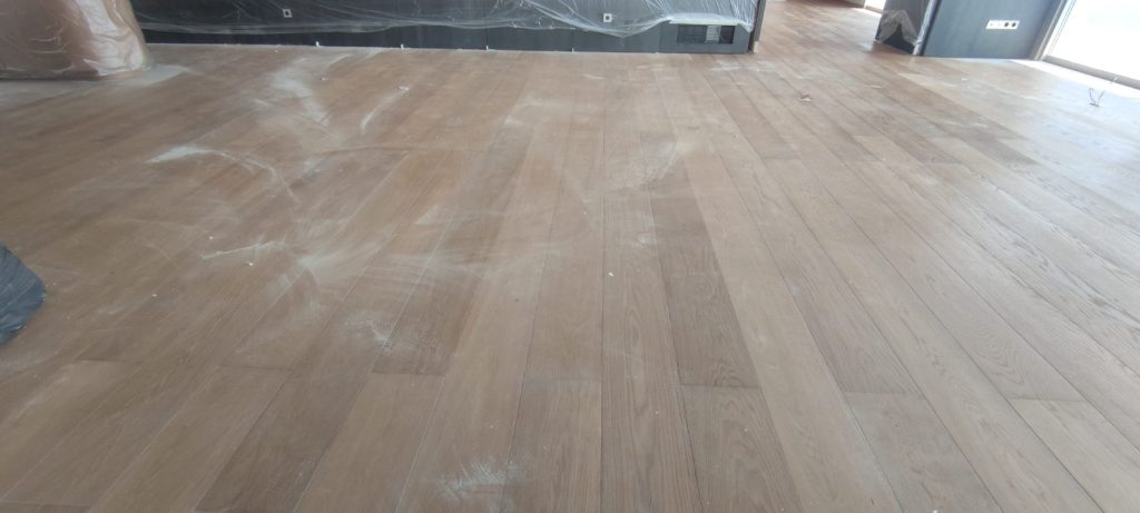 Parquet chêne à larges lames abîmé avec résidus blancs de plâtre avant intervention à Ajaccio par Caps-2B