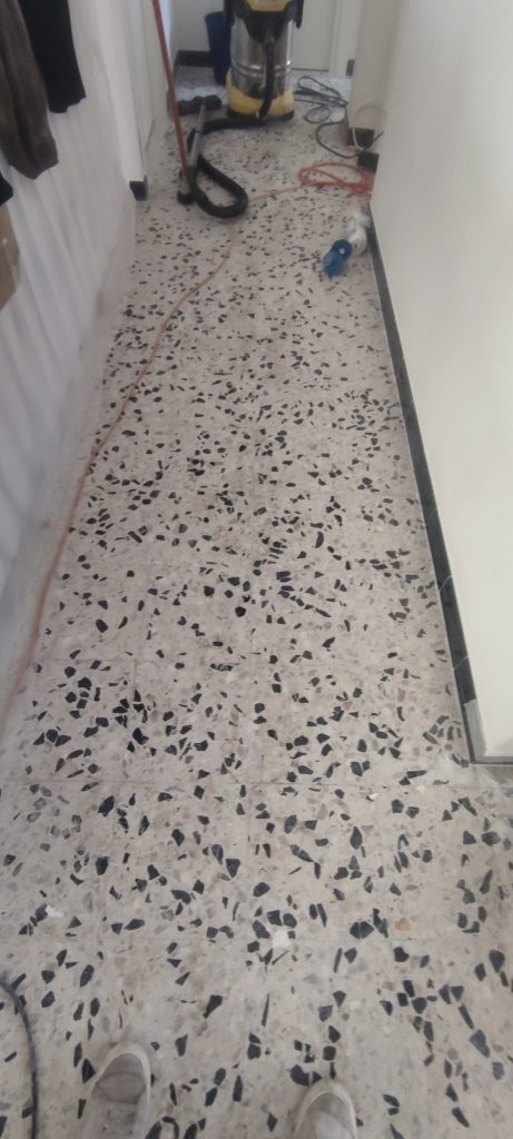 Couloir en terrazzo noir et blanc en cours de ponçage diamant avec aspirateur industriel à Ville di Pietrabugno par Caps-2B